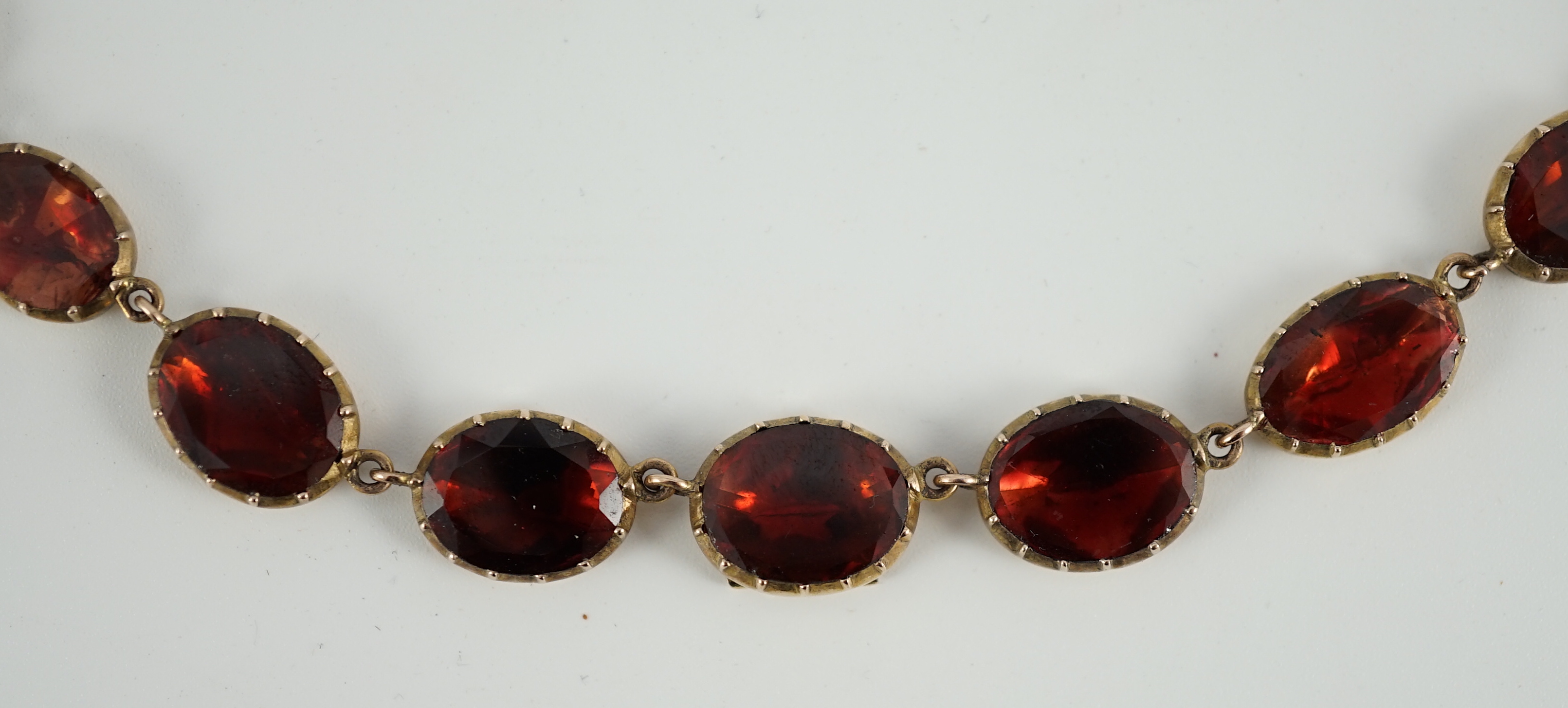 An early 19th century gold mounted graduated foil backed oval cut garnet set choker necklace